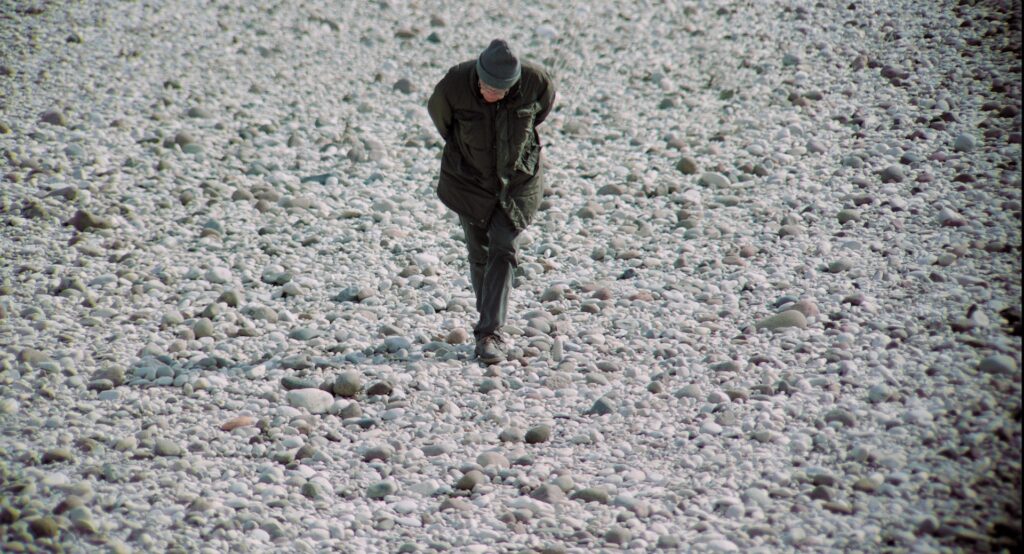 L'artista Luigi Lineri cerca sassi sul greto del fiume Adige.